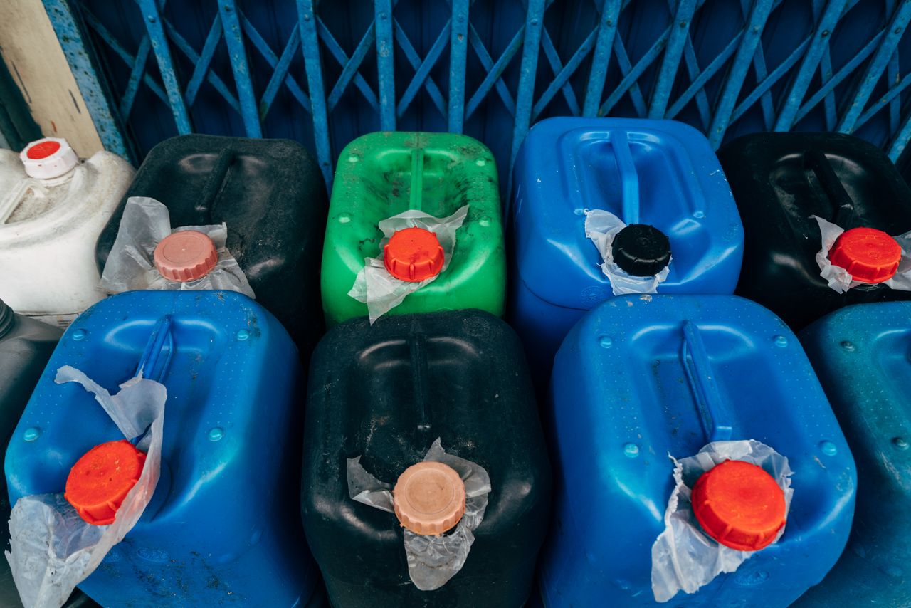 Services Top view of assorted colored plastic canisters used for industrial storage, featuring red caps.