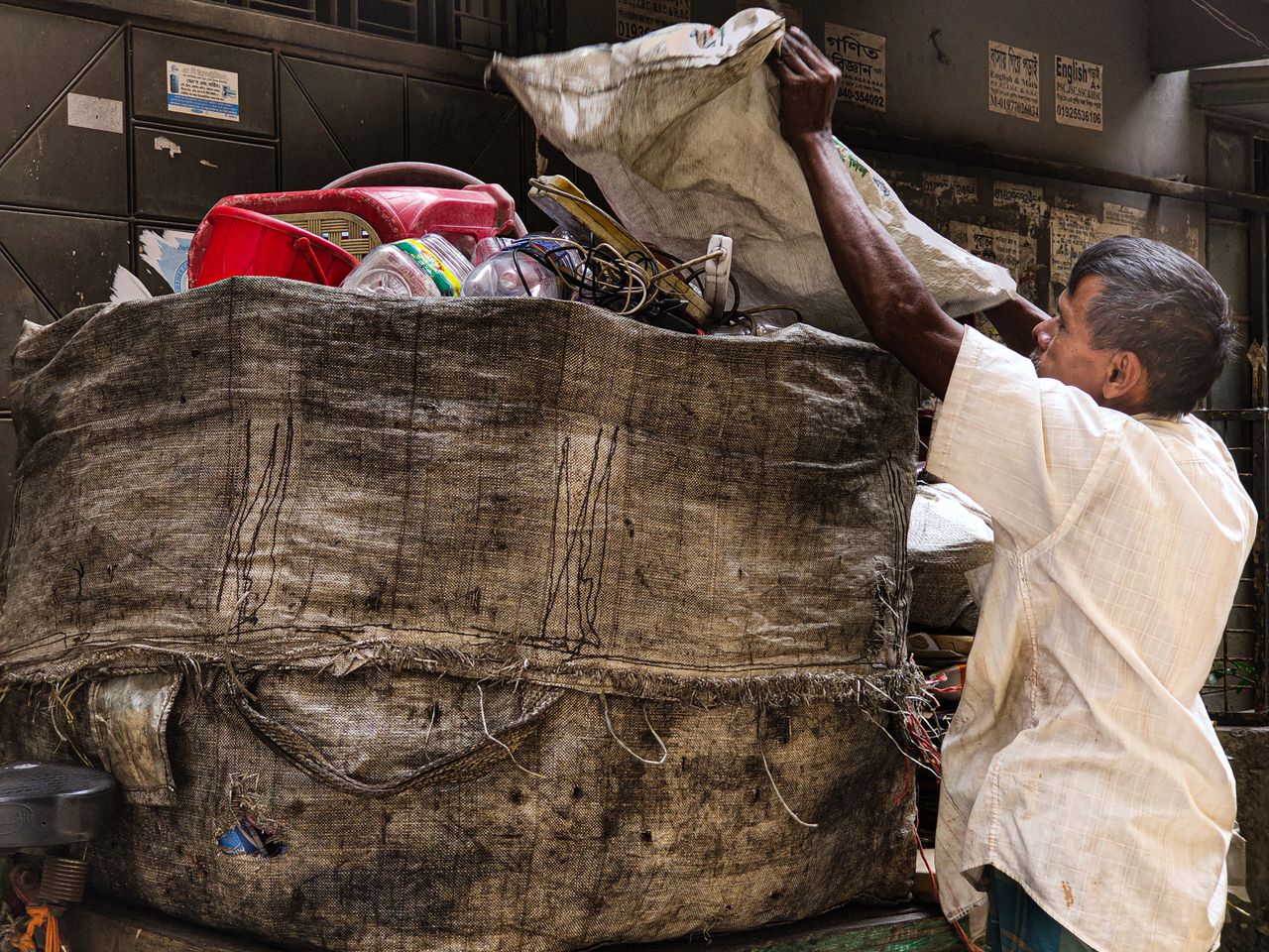 Services An adult casually sorts recyclable materials in a large sack on an urban street.