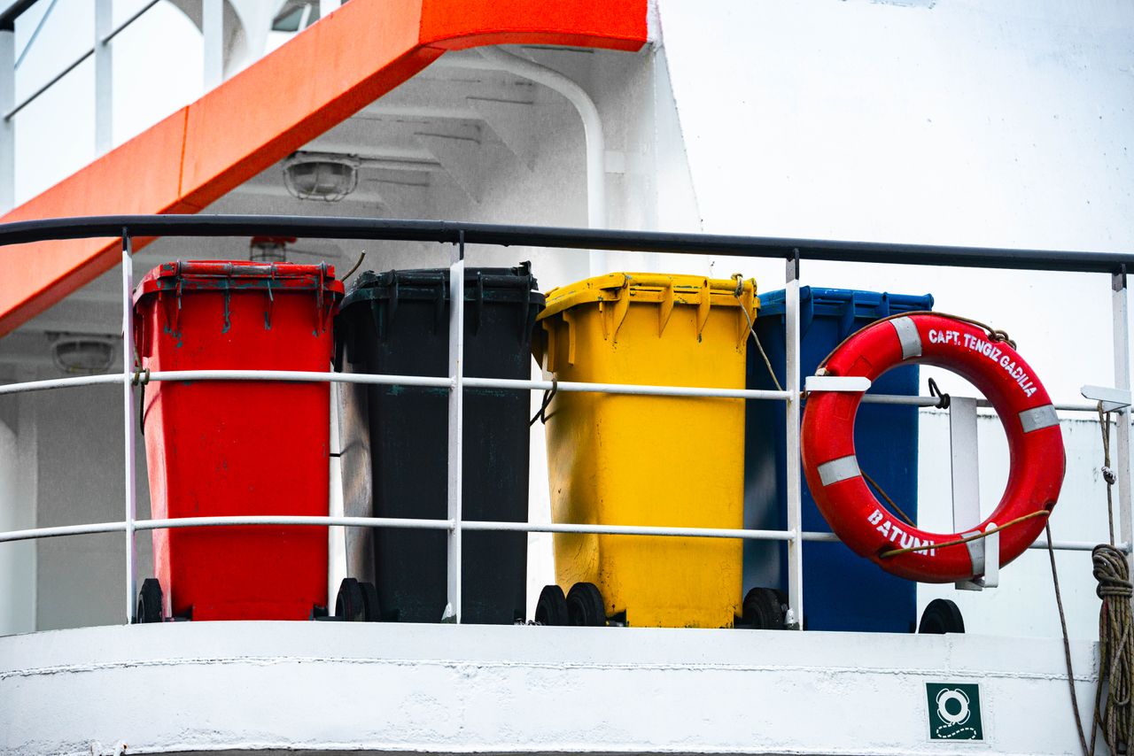 About Four colorful waste bins and a lifebuoy on a ship's deck, adding vibrant contrast.